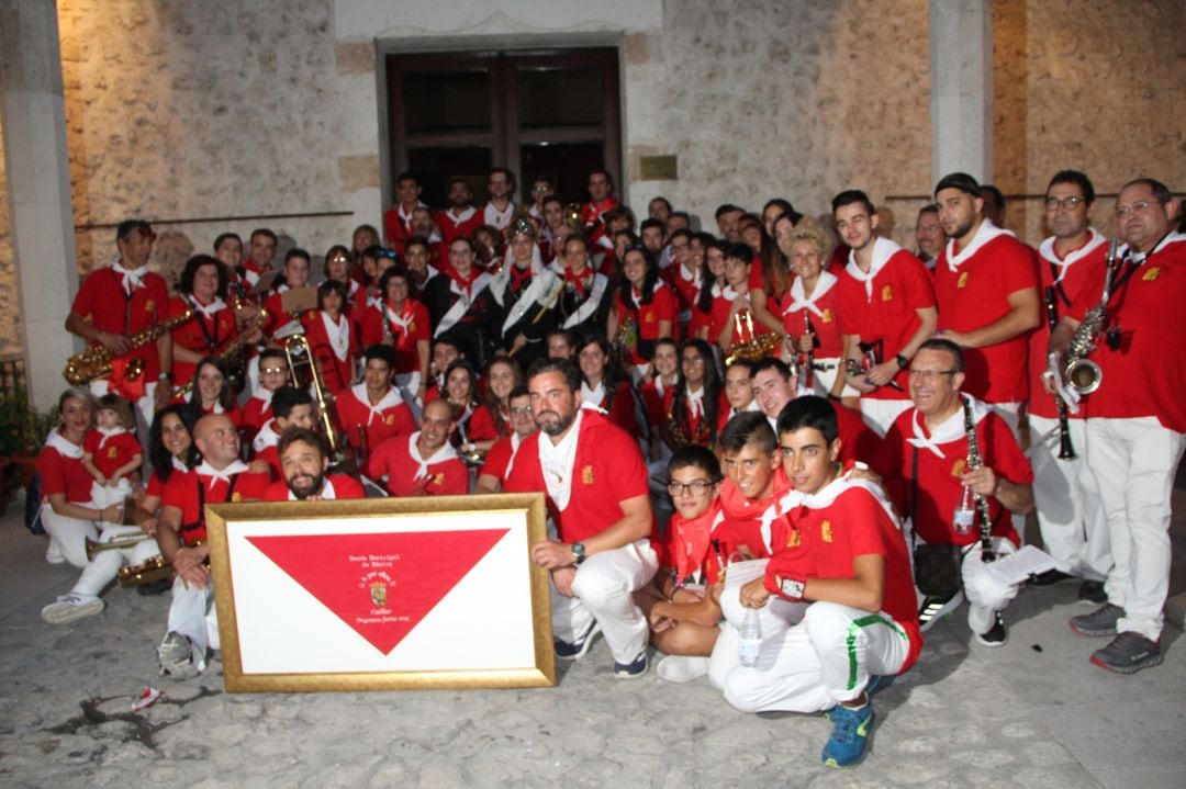 La Banda Municipal de Múscia junto a la corregidora y las damas en el patio del Ayuntamiento donde han recibido un cuadro con un gran pañuelo rojo recordando que han sido los pregoneros del 2019