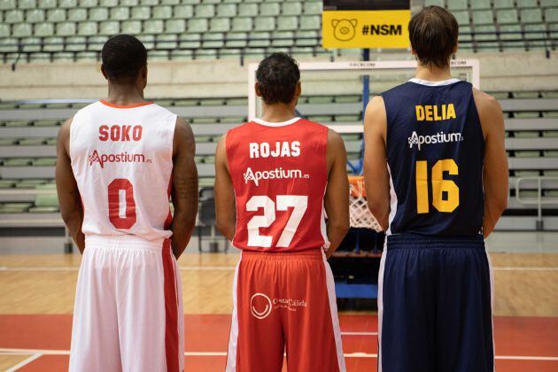 Ovie Soko, Sadiel Rojas y Marcos Delía posan de espaldas con las equipaciones del UCAM Murcia CB de la temporada 2018-2019