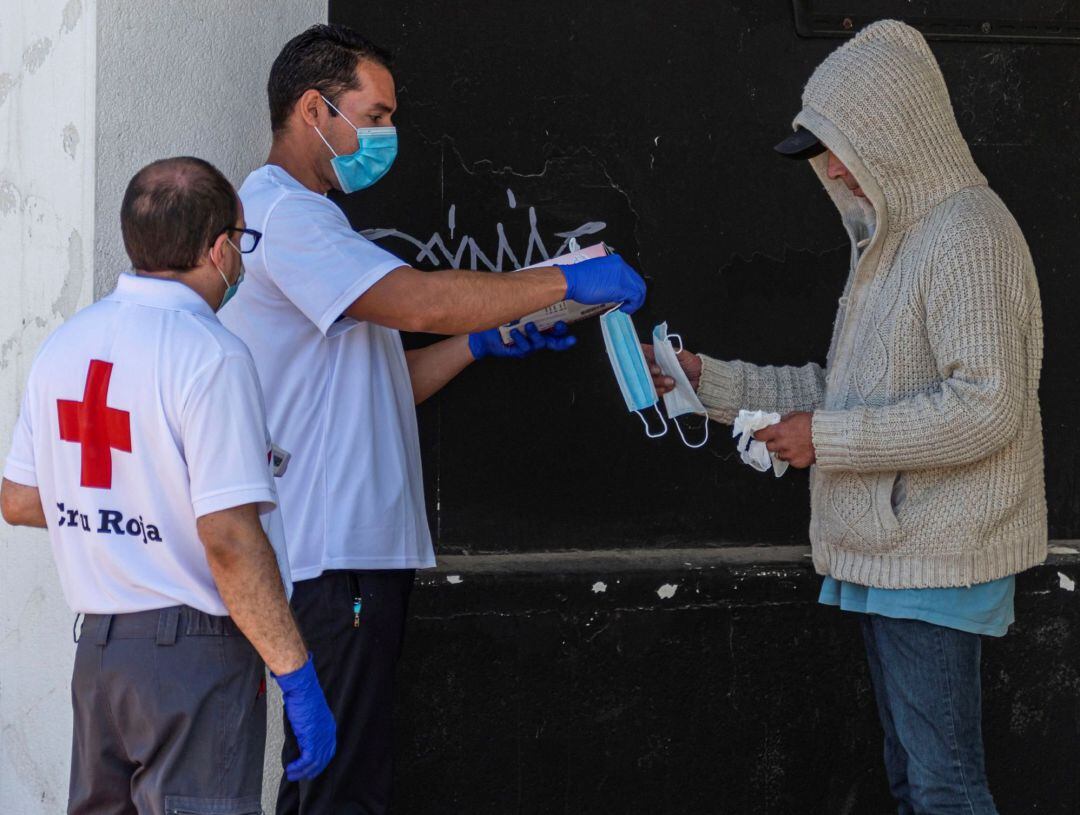 Voluntarios de Cruz Roja entegan guantes y mascarillas a un indigente en Llucmajor, Mallorca, este viernes. Voluntarios de la Cruz Roja entregan mascarillas, guantes y comida, diariamente, a personas que viven en la calle.