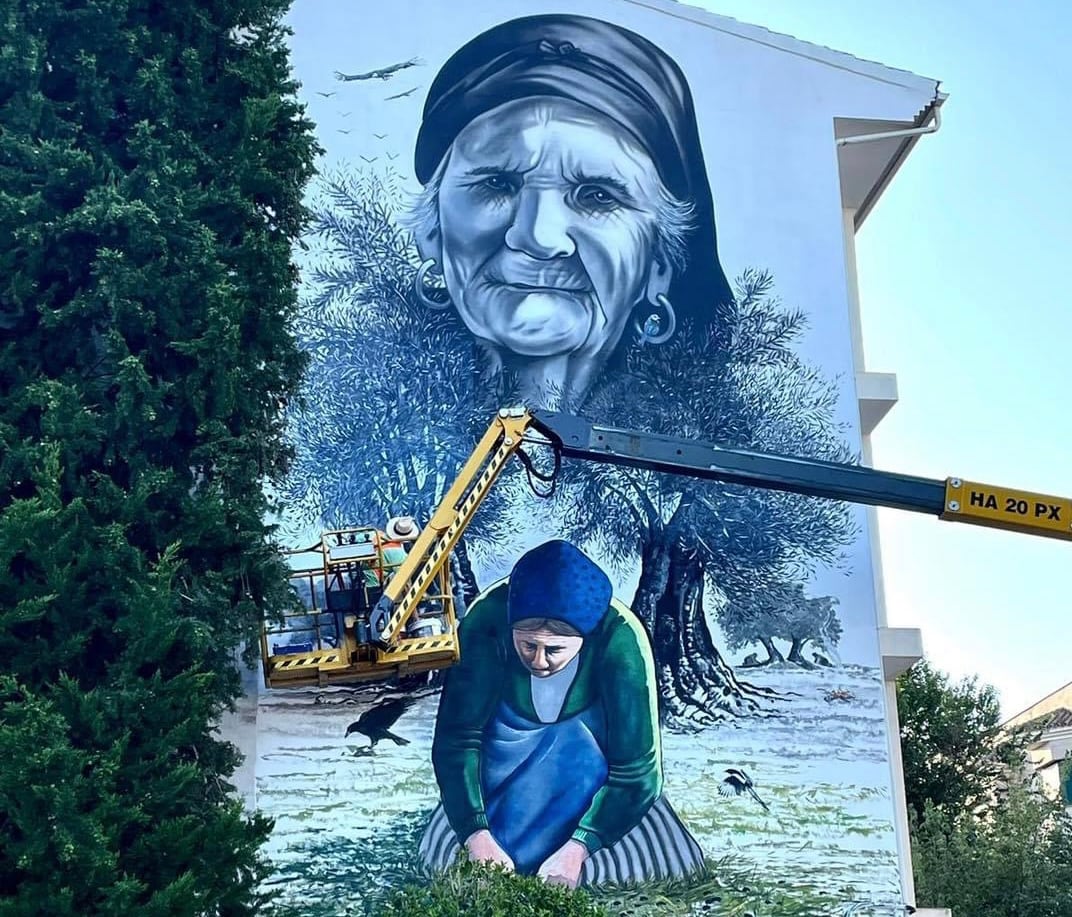 El artista Faustino Castillo, subido a una grúa pintando uno de los murales.