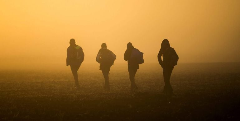 Refugiados caminan por el campo para evitar los controles de la policía en las vías del tren que conectan Horgos Szeged cerca de Roszke en Hungría