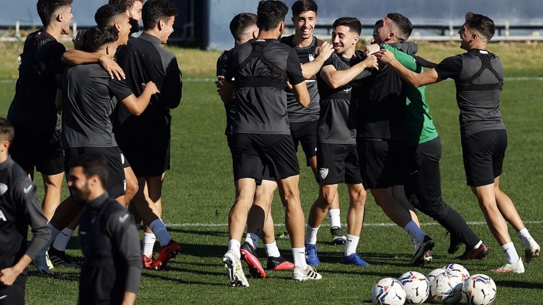 Varios jugadores del Málaga se abrazan durante el entrenamiento del jueves