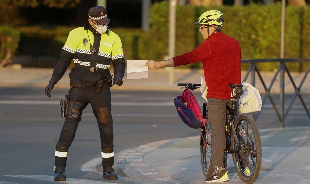 La policía local pide los papeles a un ciudadano que circulan por la calle esta tarde durante el décimo cuarto día de confinamiento tras la declaración del estado de alerta por coronavirus.