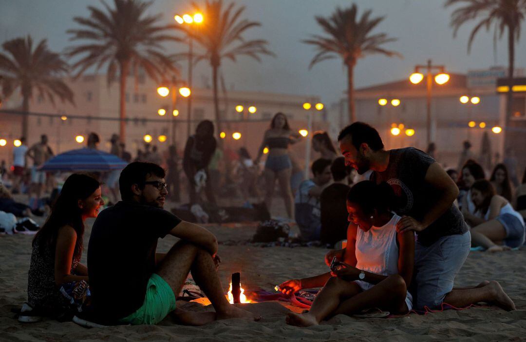 Un grupo de jóvenes bromean junto a la hoguera que han encendido, en la playa de la Malvarrosa de Valéncia, para celebrar la Noche de San Juan.