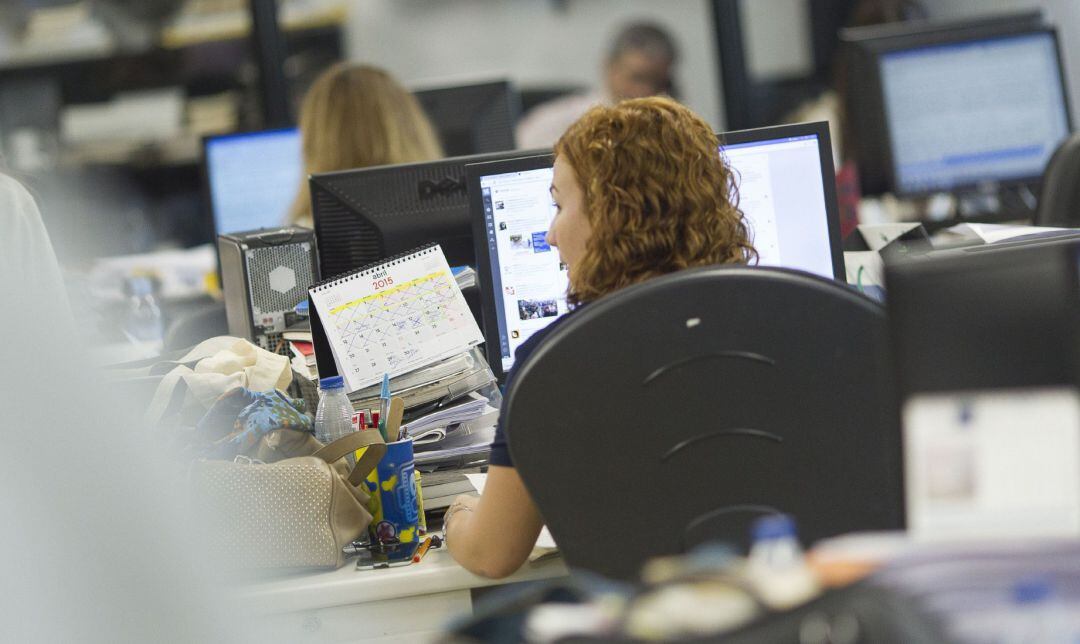 Una mujer trabaja en una oficina con un ordenador.