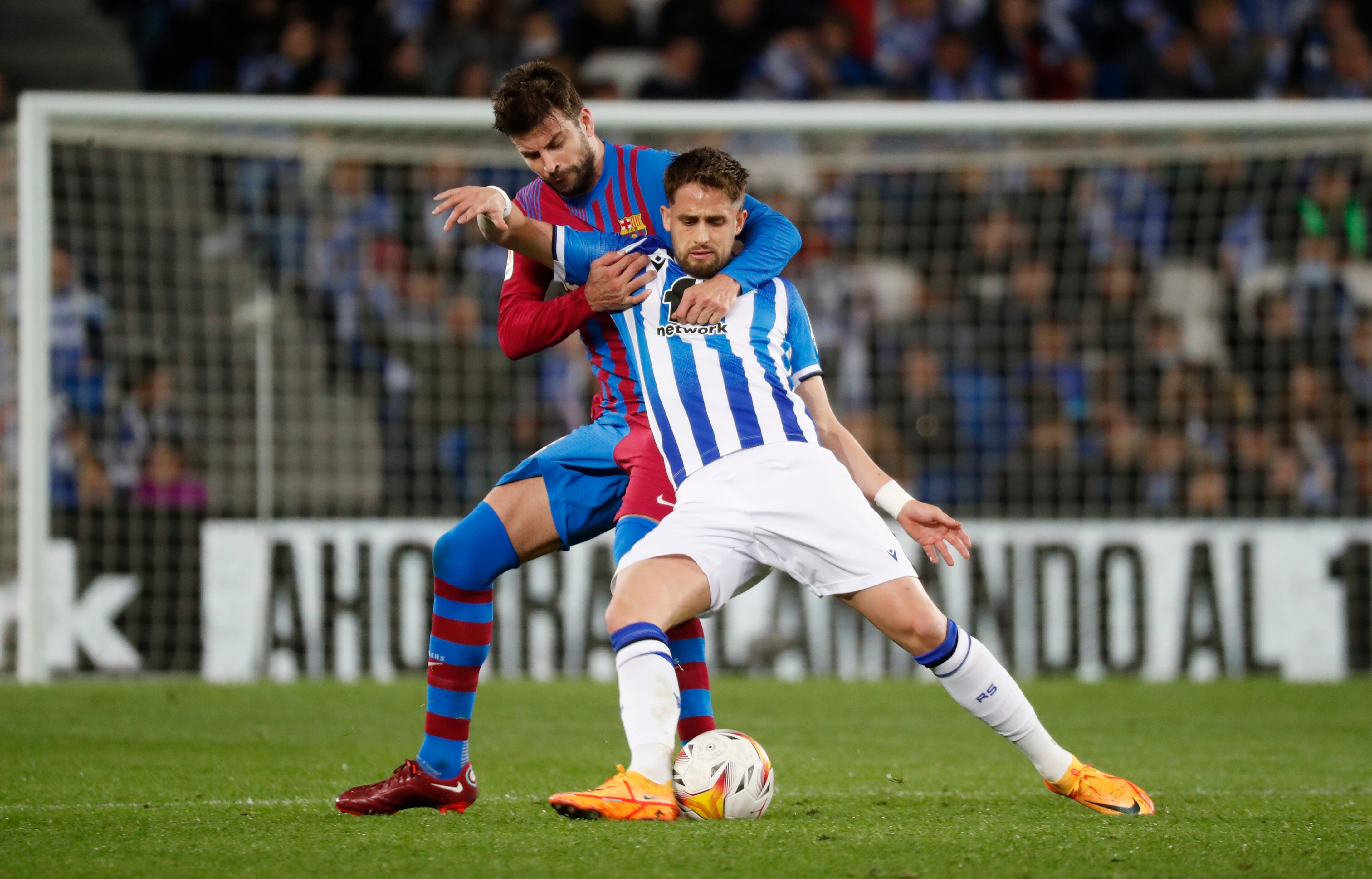 SAN SEBASTIÁN, 21/04/2022.- El centrocampista belga de la Real Sociedad, Adnan Januzaj, protege el balón ante el defensa del FC Barcelona, Gerard Piqué, durante el encuentro correspondiente a la jornada 33 disputado hoy jueves en el Reale Arena de San Sebastián. EFE / Juan Herrero.
