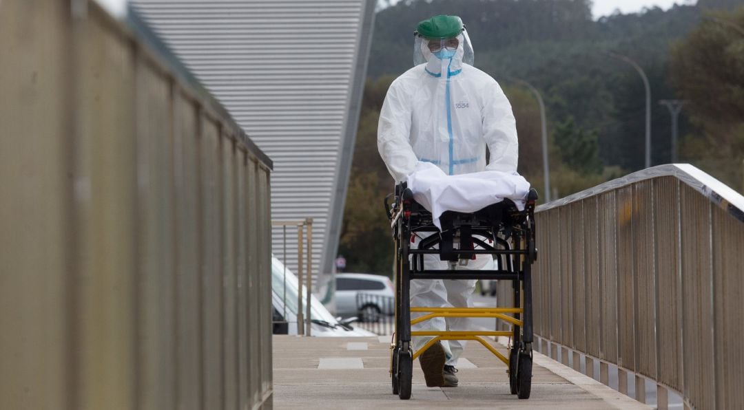 Un trabajador sanitario totalmente protegido traslada una camilla en las inmediaciones de la residencia de ancianos de San Cibrao, Lugo, en 9 de noviembre de 2020. 