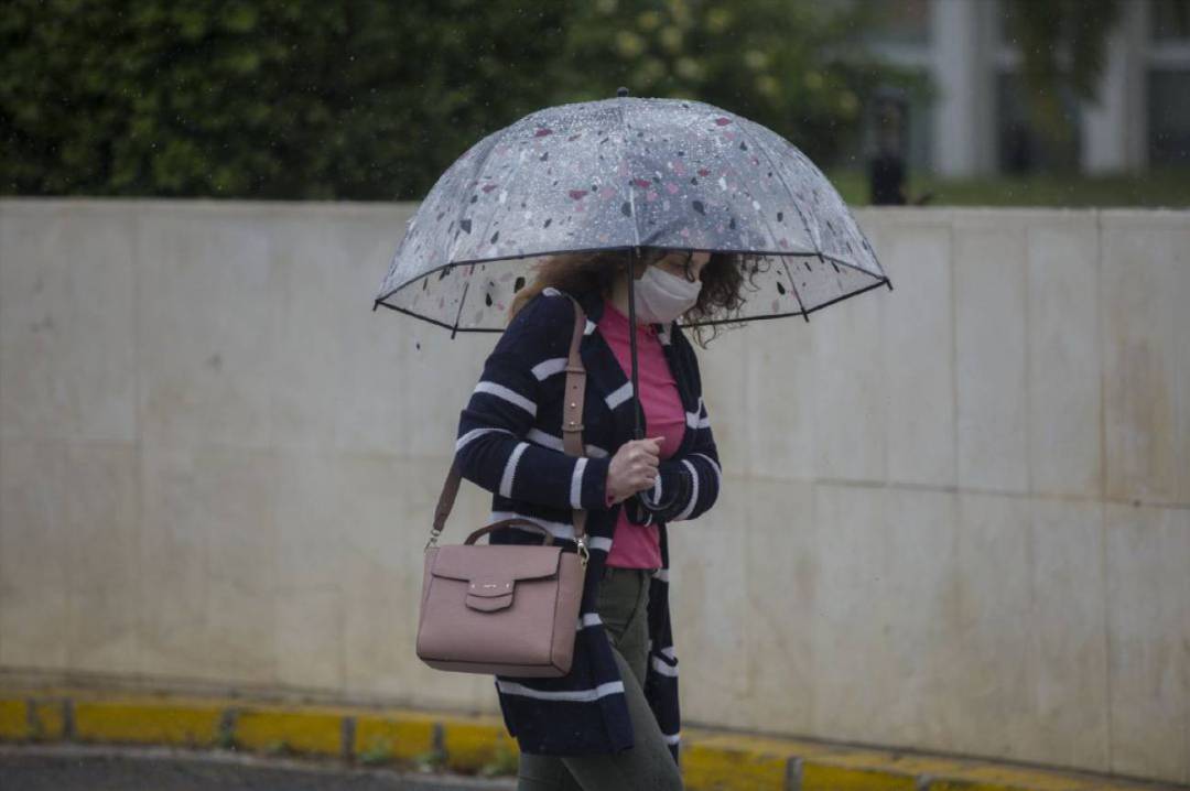 Una mujer con su paraguas bajo la lluvia, en Sevilla