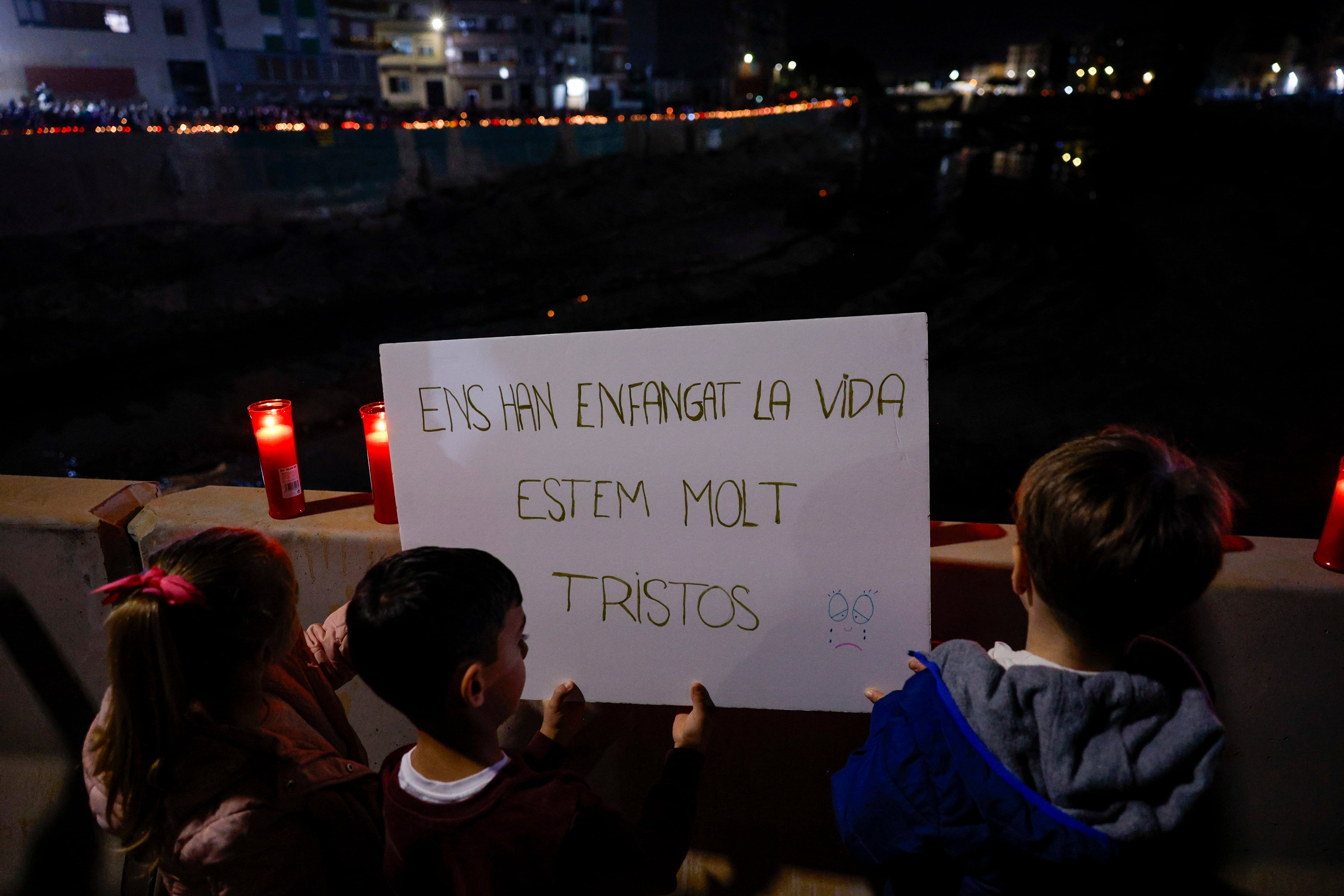 Unos niños portan una pancarta en el homenaje en el barranco del Poyo a los fallecidos por la dana que arrasó parte de la zona, cuando se cumple un mes de la catástrofe.