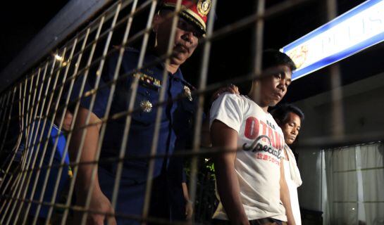 Un policía vigila a delincuentes detenidos en Manila en operaciones antidrogas.