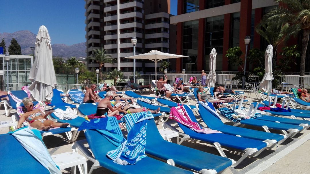 Turistas tomando el sol en una piscina de Benidorm.