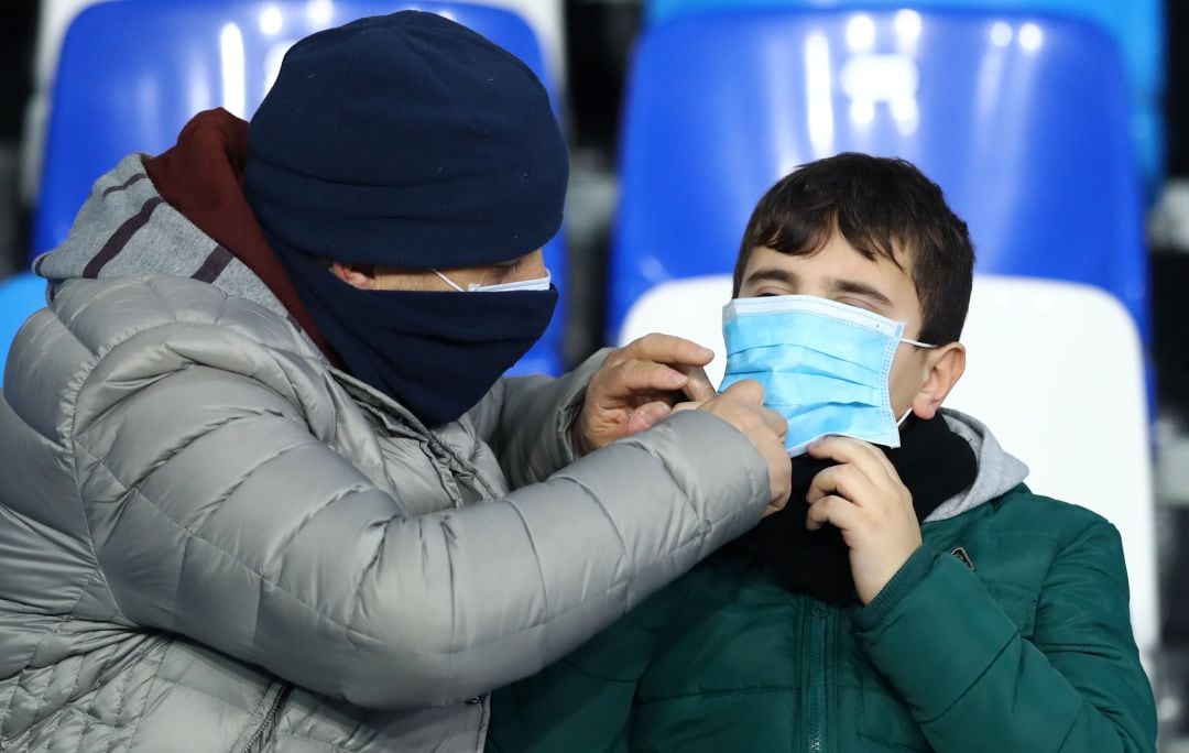 Un adulto coloca la mascarilla a un menor