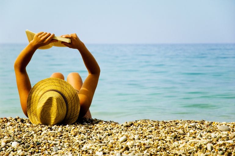 Una chica lee en la playa durante sus vacaciones de verano