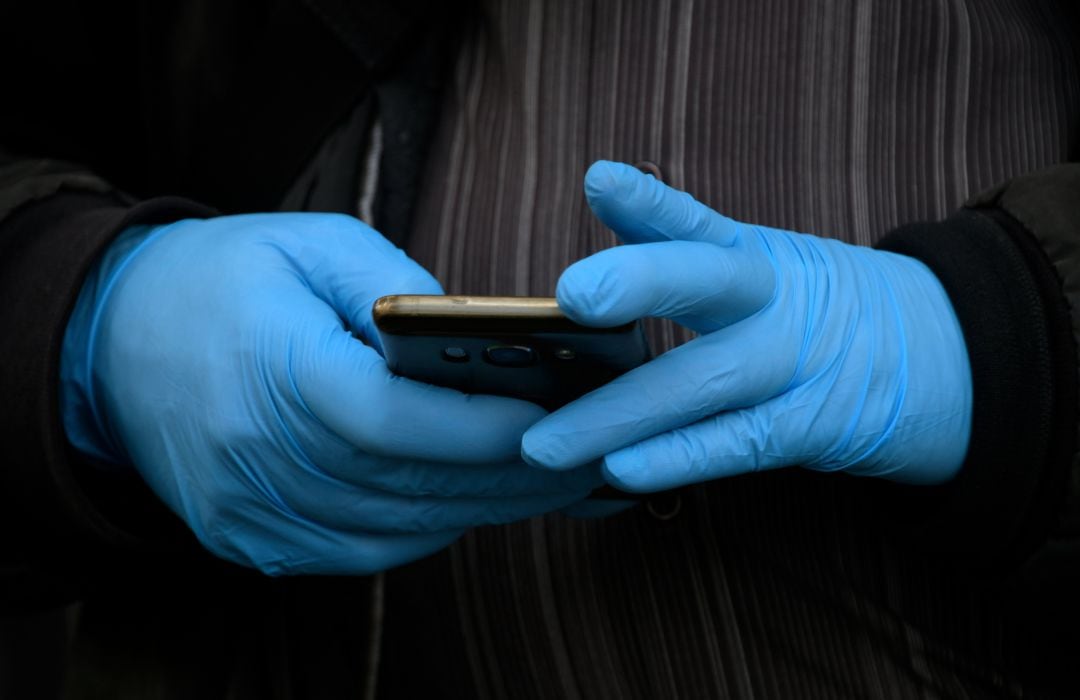 Un hombre con guantes maneja un smartphone en Madrid.