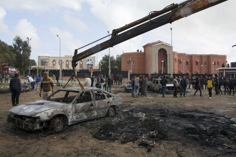 Una grua retira los restos de un vehículo calcinado por la explosión en la ciudad de Shahat, frente al edificio en el que el enviado de la ONU Bernardino León iba a reunirse con el primer ministro Al Thini