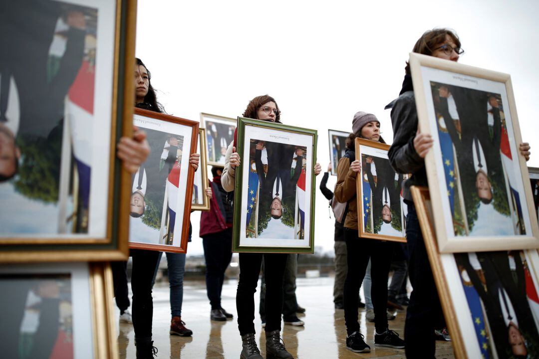 Los activistas climáticos franceses tienen retratos invertidos del presidente francés Emmanuel Macron durante una protesta por el cambio climático frente a la Torre Eiffel