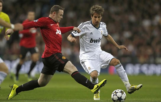 El defensa portugués del Real Madrid Fábio Coentrao lucha un balón con el delantero del Mancherter United Wayne Rooney, durante el partido de ida de los octavos de final de Liga de Campeones que ambos equipos disputan en el estadio Santiago Bernabéu