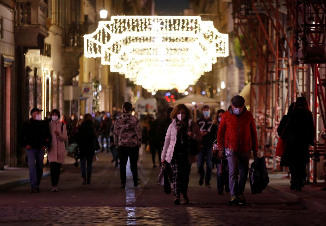 People wearing protective masks walk along Via dei Condotti in Rome, Italy 