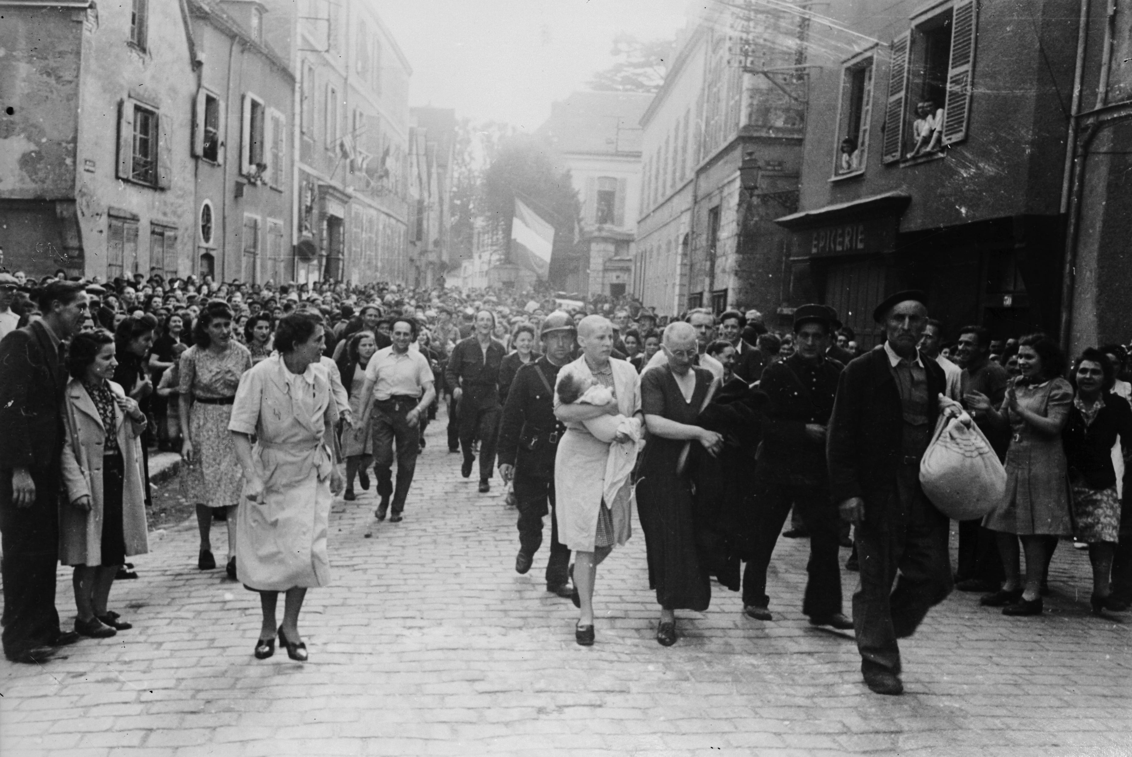 A woman, with her baby whose father is German, and her mother are jeered and humiliated by crowds in Chartres after having their heads shaved as punishment for collaborating with the German troops.   (Photo by Robert Capa/Getty Images)