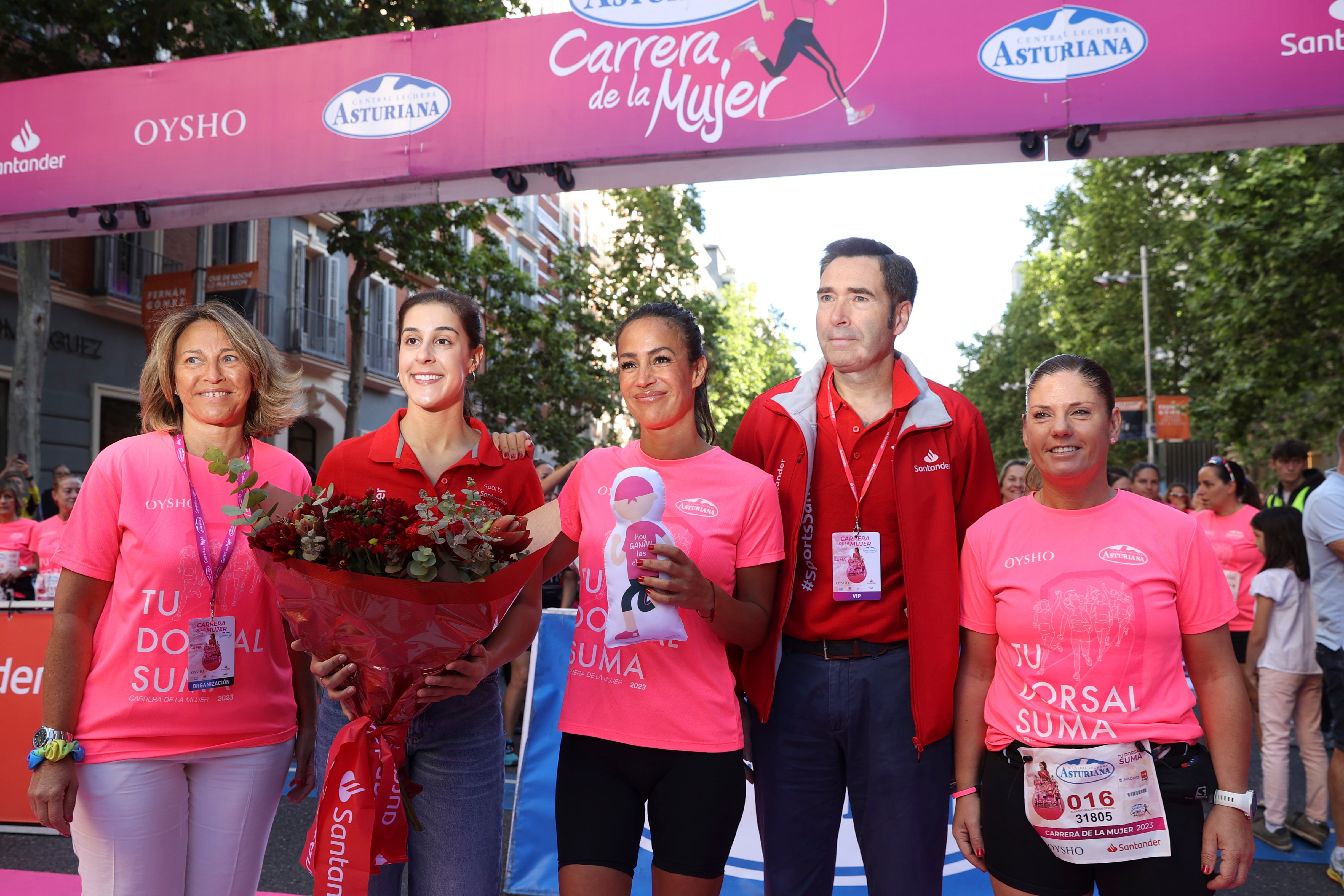 La triple campeona del mundo de bádminton Carolina Marín (2i), la vicealcaldesa de Madrid, Begoña Villacís (c), y el director de patrocinios del Banco Santander, Felipe Martín (2d), entre otros, posan antes de comenzar la Carrera de la Mujer, este domingo, en Madrid.