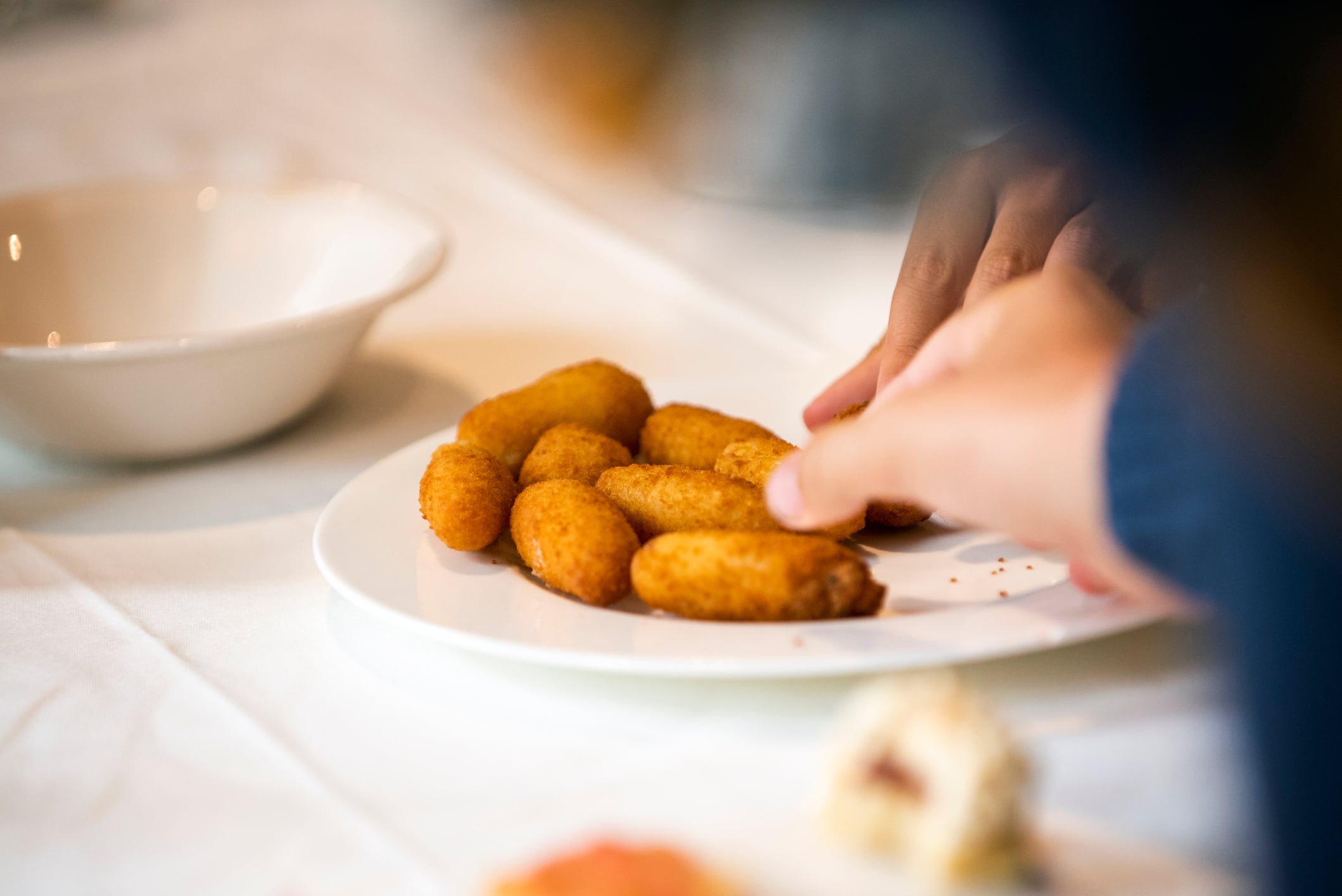 Varias personas cogiendo croquetas de un plato.