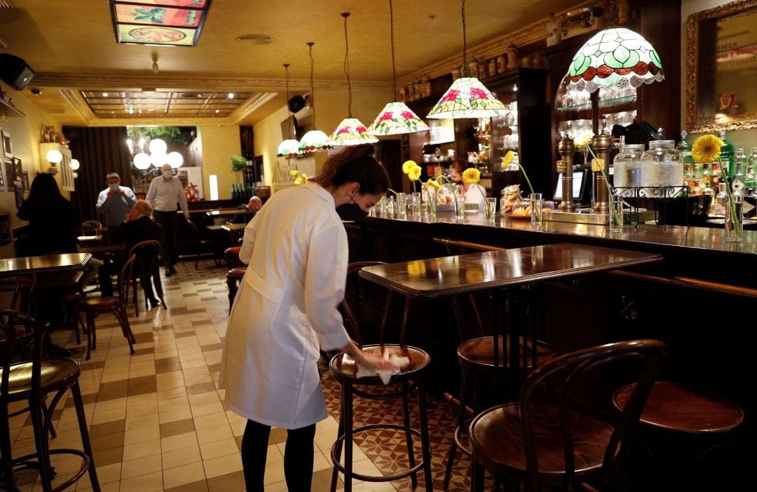 Una camarera desinfecta una silla en un bar de Pamplona en el primer día de la fase 2 de desescalada en el que se permite el consumo en el local en mesa sin superar el 40% del aforo y manteniendo las medidas de seguridad e higiene establecidas