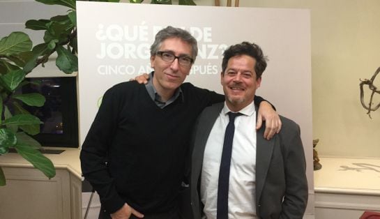 David Trueba y Jorge Sanz posan tras la entrevista delante del cartel promocional de la serie