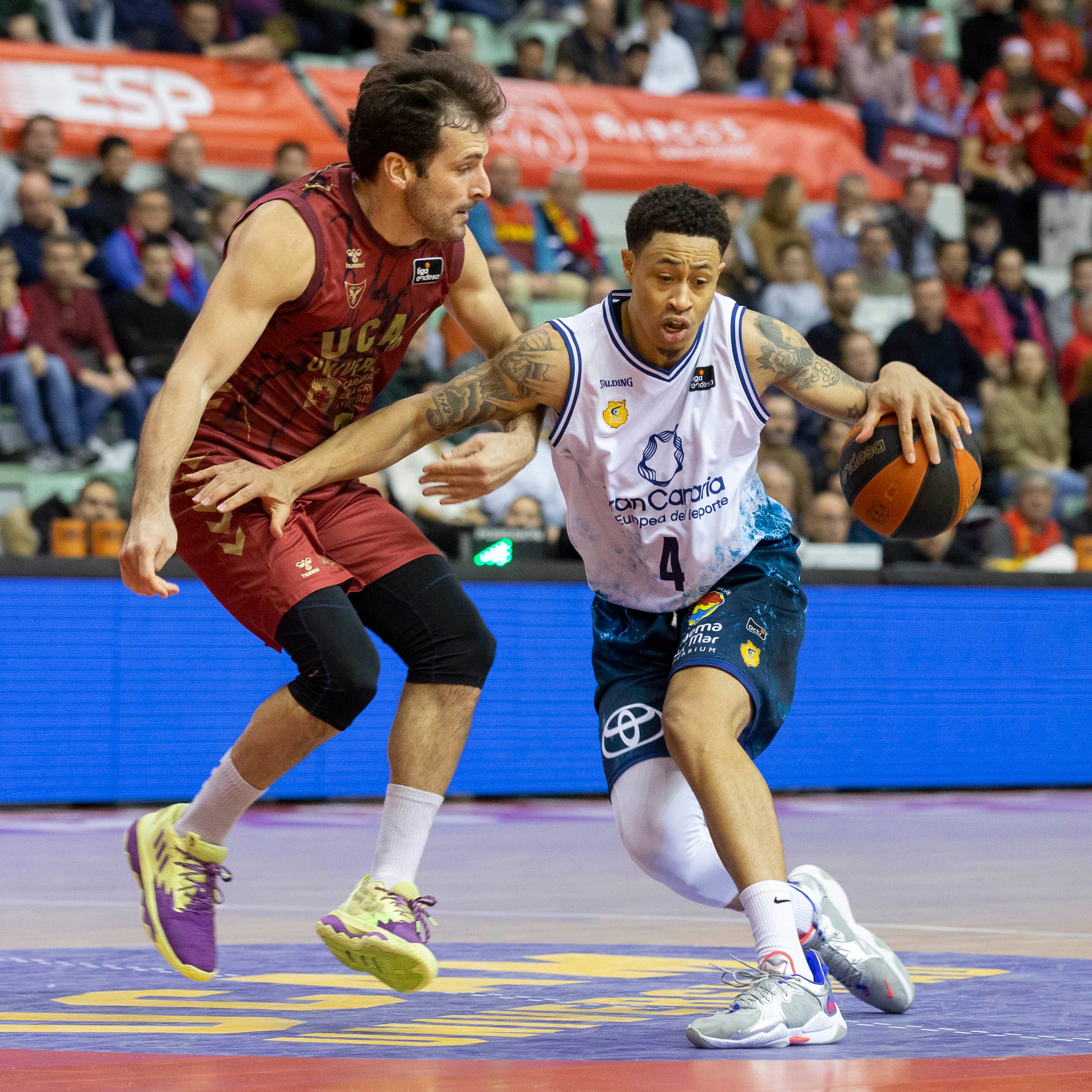 MURCIA, 17/12/2022.- El escolta polaco de Gran Canaria AJ Slaughter (d) bota el balón ante la oposición del base Tomás Bellas (i), de UCAM Murcia, durante el partido de la décimo segunda jornada de la Liga Endesa entre UCAM Murcia y CB Gran Canaria, este sábado en el Palacio de los Deportes de Murcia. EFE/Marcial Guillén
