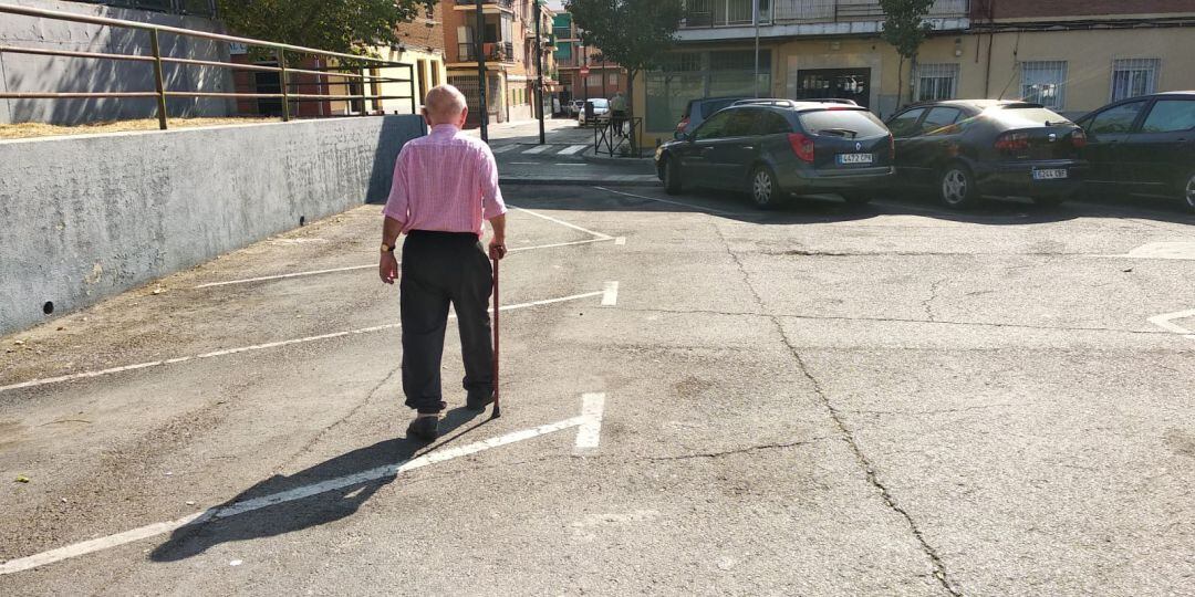 Persona mayor camina sola por una calle.