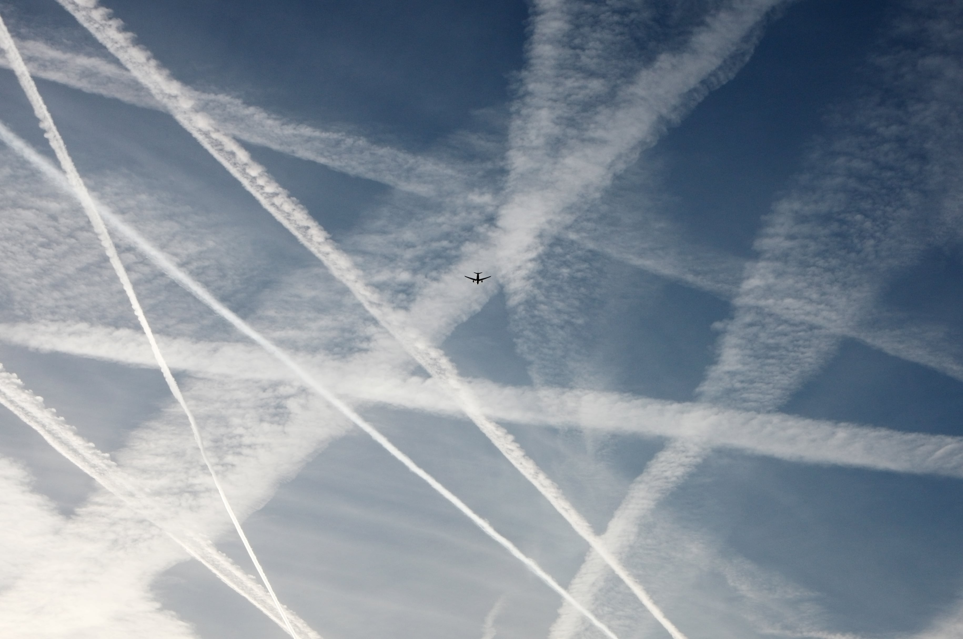 Airplane flying through a sky full of vapour trails