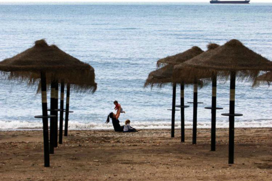 Una mujer con dos niños en la playa de La Malagueta 