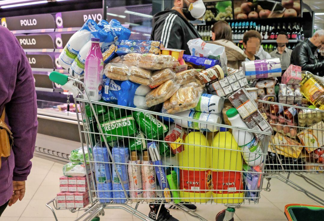 Un cliente realiza la compra en un supermercado un día marcado por colas de gente deseosas de hacer acopio de alimentos y otros productos debido al avance del coronavirus en España.