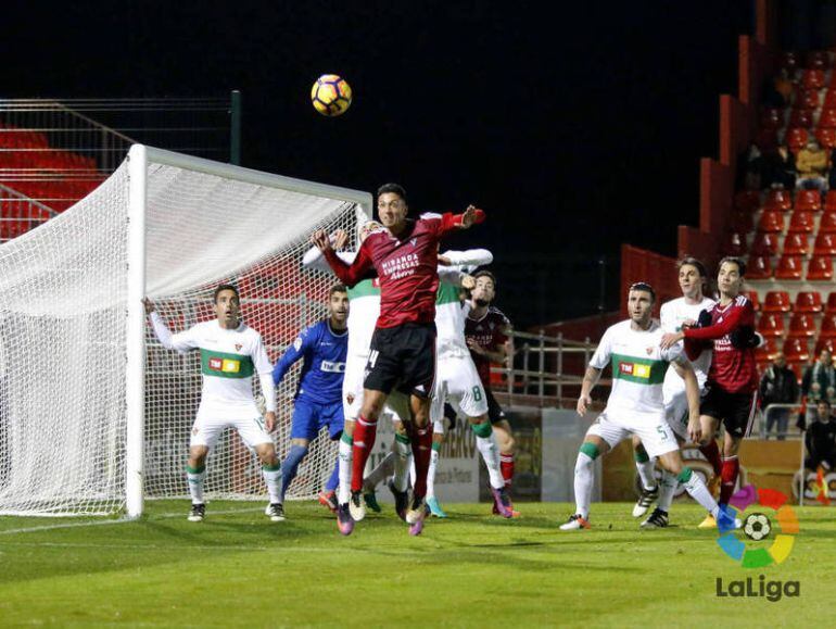 Mesa salta por un balón ante dos defensas del Elche C.F.