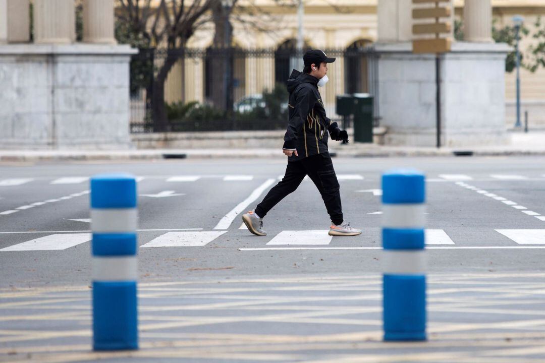Un hombre camina por el centro de Málaga protegiéndose con una mascarilla y guantes, hoy sábado durante el confinamiento por el Estado de Alarma para evitar la propagación del coronavirus