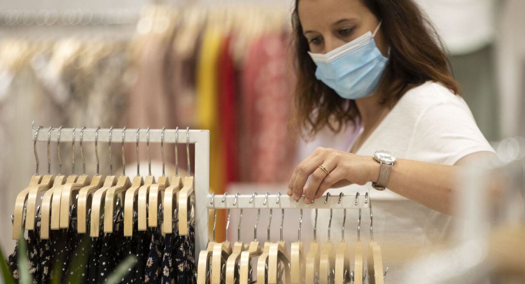 Mujer con mascarilla en una tienda de ropa.