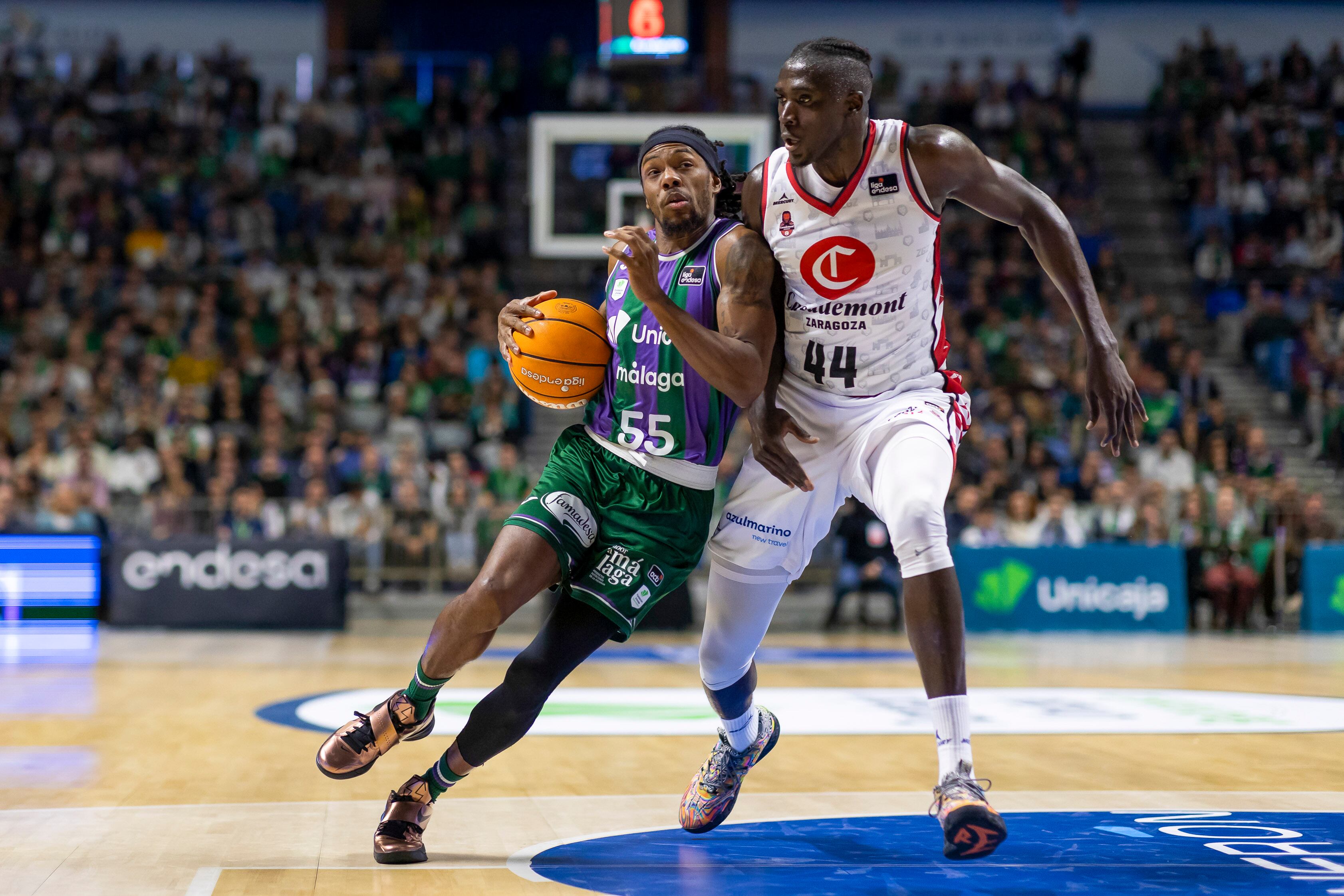 MÁLAGA, 04/01/2025.- El base estadounidense del Unicaja, Kendrick Perry (i) entra a canasta ante el pívot angoleño del Casademont Zaragoza, Jilson Bango (d), durante el partido de la decimoquinta jornada de la liga Endesa disputado este sábado en el Palacio de Deportes José María Martín Carpena.- EFE/ Carlos Díaz
