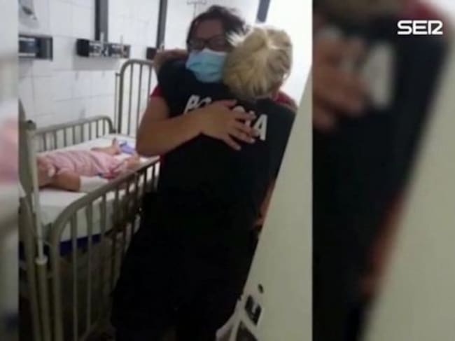 La madre de la niña abraza a la agente que le salvó la vida.
