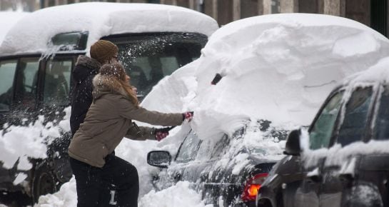 Una pareja quita la nieve de su coche en la localidad cántabra de Reinosa