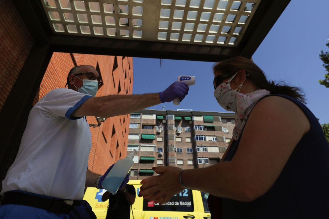 Un trabajador sanitario toma la temperatura a una vecina antes de su acceso al centro sanitario para realizarse una prueba PCR