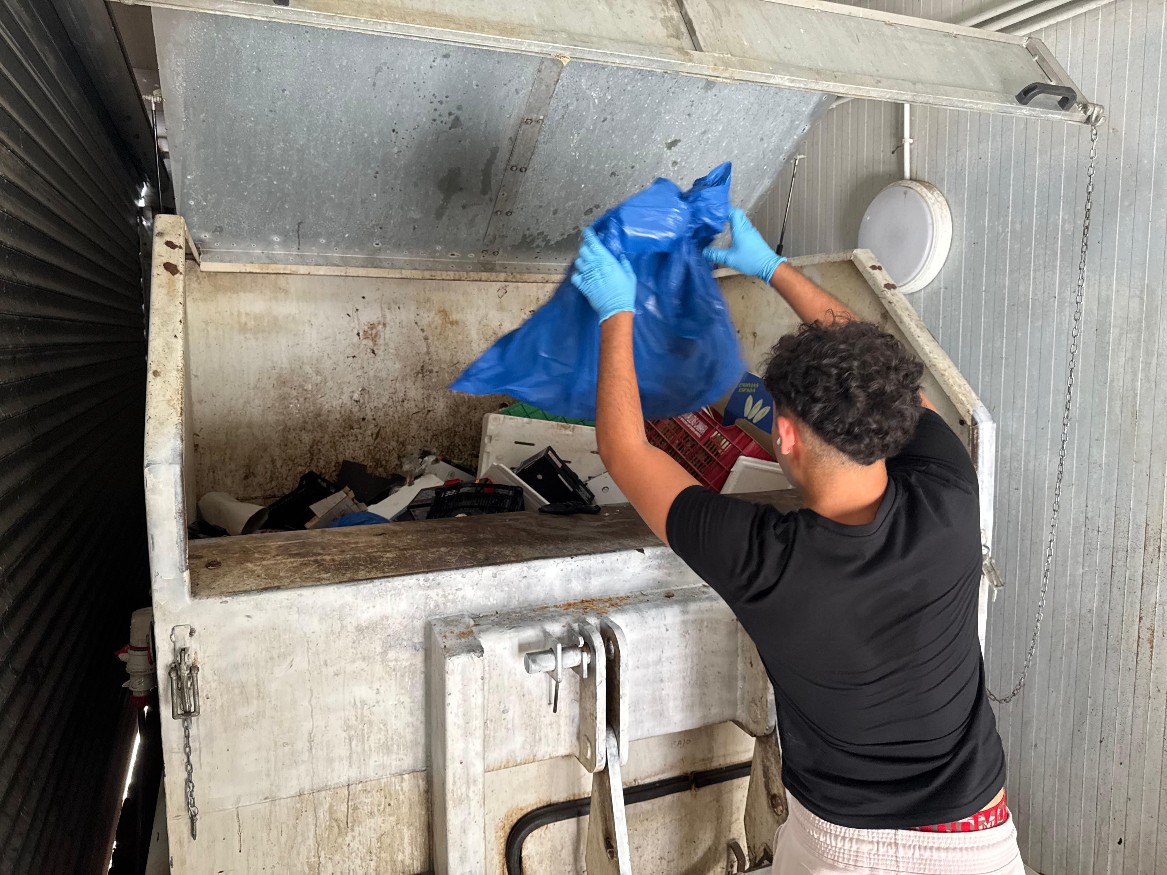 Un empleado del Mercado Municipal de Alicante deposita restos en el contenedor