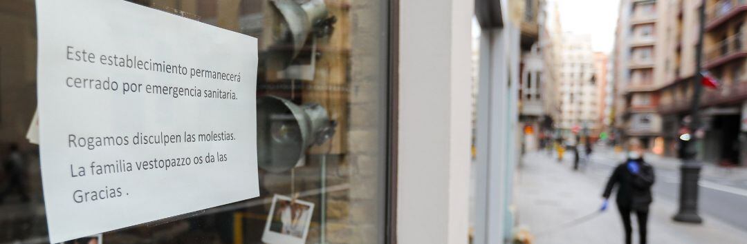 Cartel en la ventana de un establecimiento cerrado en una calle prácticamente vacía 