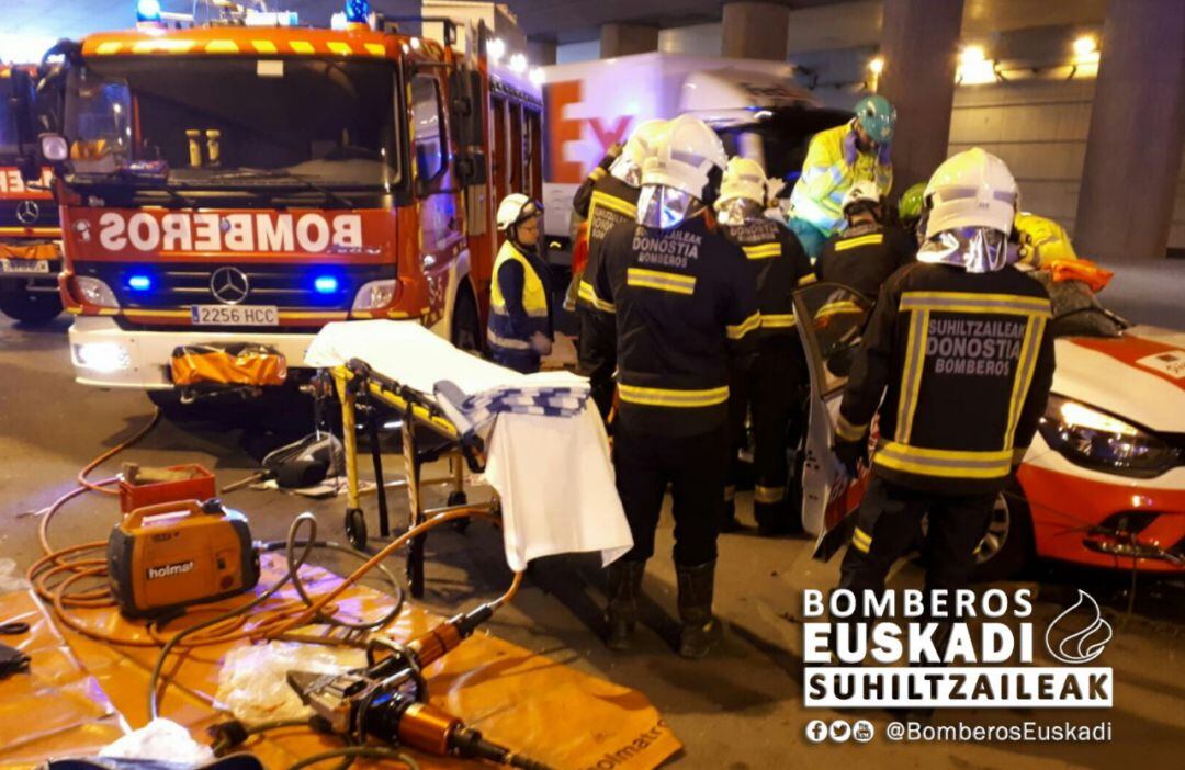 Los bomberos trabajan para liberar a la persona que ha quedado atrapada tras chocar su coche contra un camión en Urnieta.