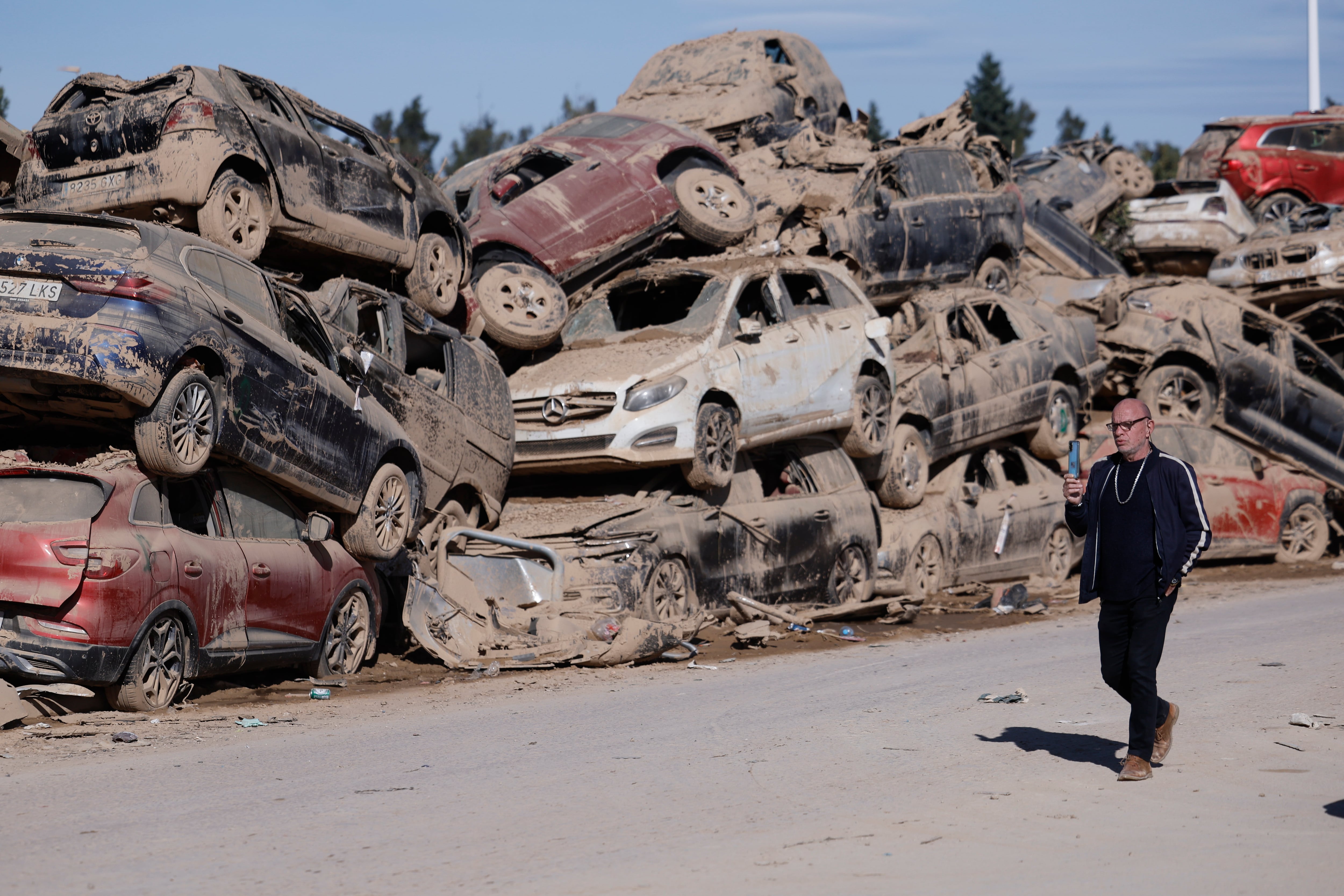 Catarroja (Valencia), 29/10/2025.- Un hombre pasa ante los innumerables coches apilados, el 20/11/2024. La dana del 29 de octubre de 2024 dejó 229 fallecidos, 2.641 heridos y casi 18.000 millones de euros en daños económicos. EFE/Archivo/Kai Försterling
