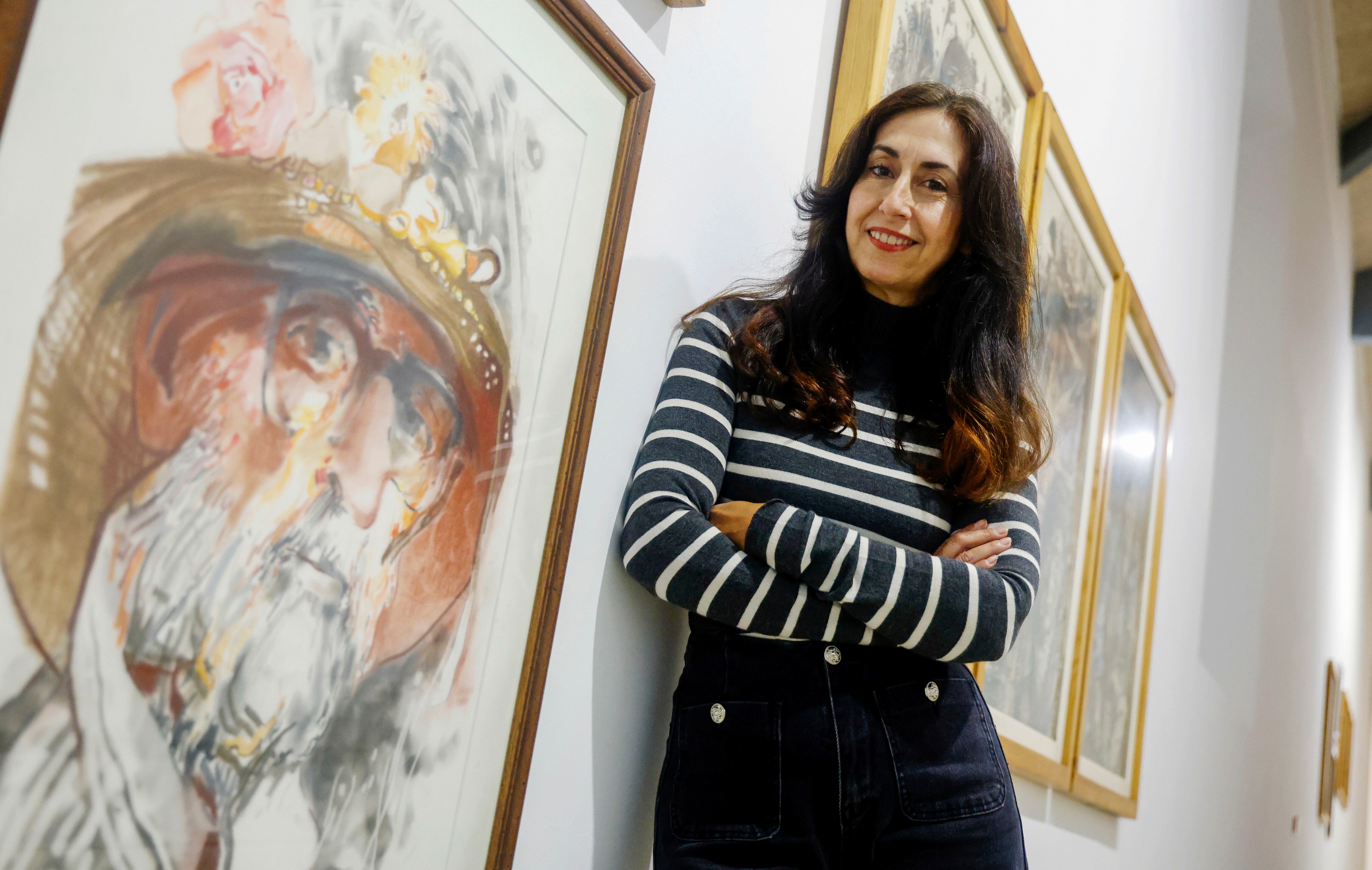Helena, hija del pintor ferrolés Ricardo Segura Torrella, posa ante obras de su padre que forman parte de la retrospectiva (foto: Kiko Delgado / EFE)