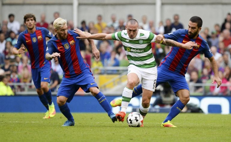 El centrocampista del Celtic de Glasgow Scott Brown pelea un balón con el delantero del FC Barcelona Leo Messi (y el centrocampista Arda Turan durante el partido amistoso de pretemporada que ambos equipos disputaron en el estadio Aviva de Dublín.