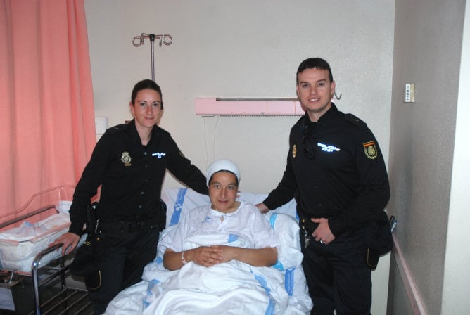 Dos agentes de la Policía Nacional junto a la mujer a la que han ayudado a dar a luz en plena calle