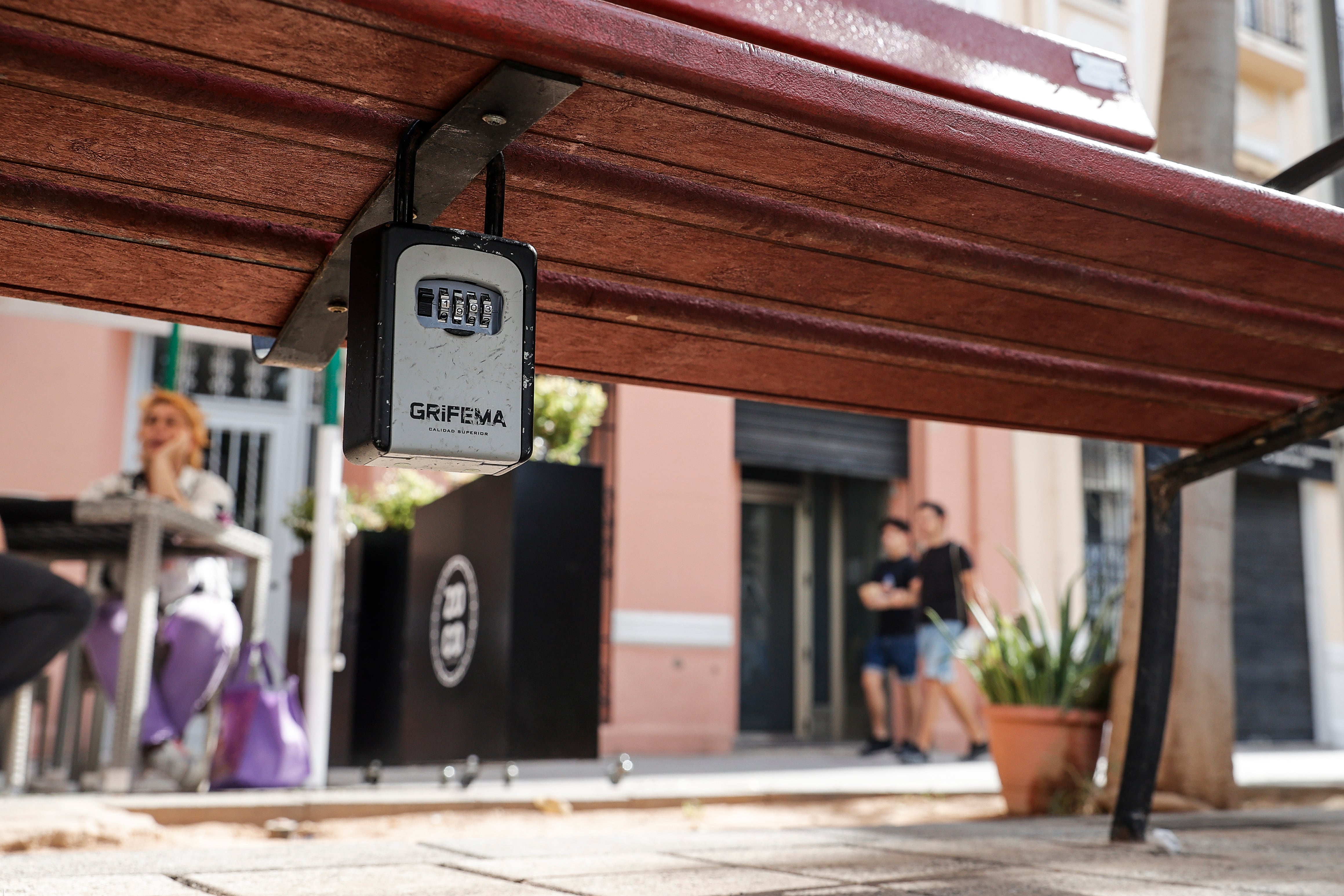 Un cajetín con las llaves de una vivienda turística colocado en un banco público en una plaza de la ciudad de València