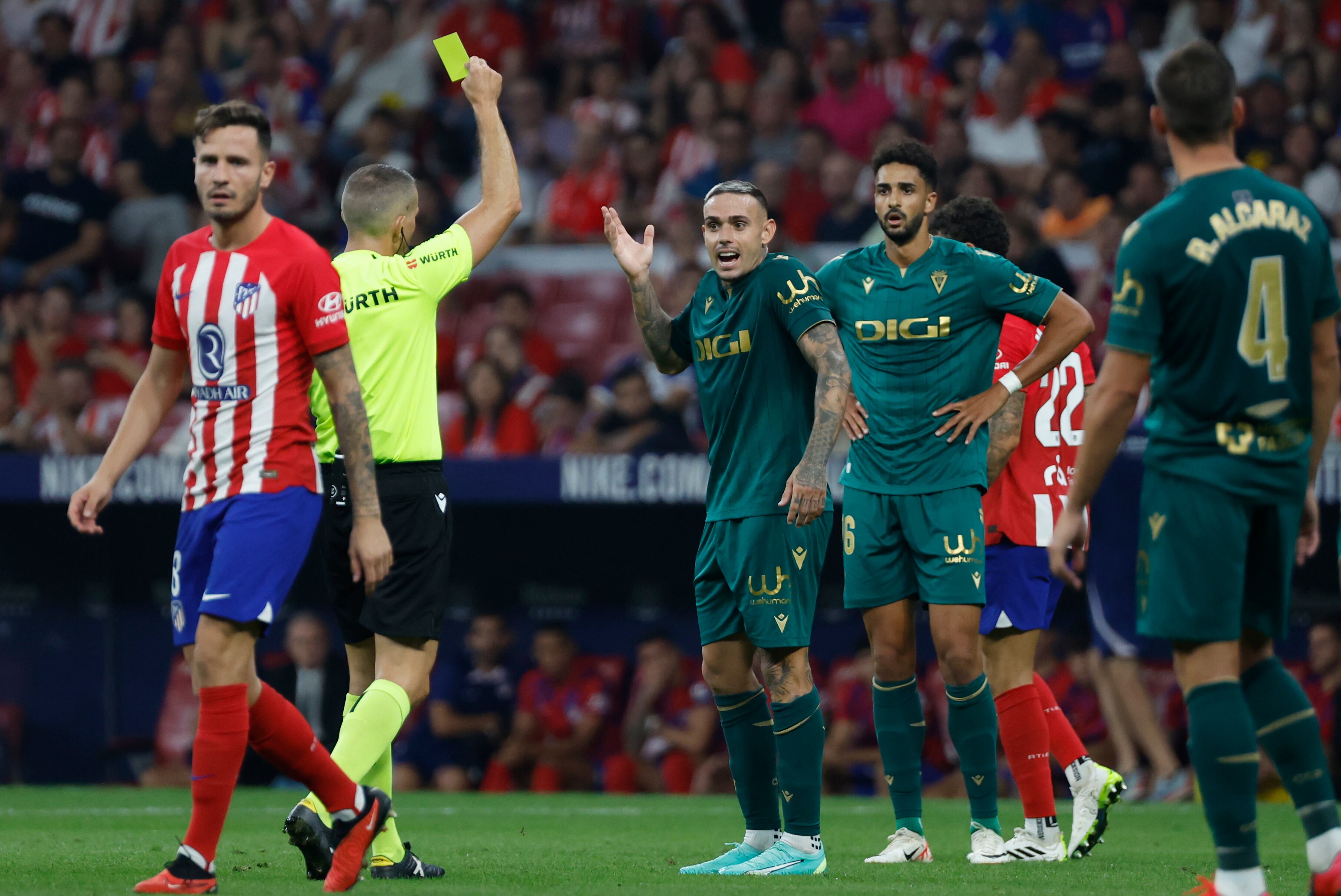 MADRID, 01/10/2023.- El colegiado muestra cartulina amarilla al delantero del Cádiz Roger (c) durante el partido de LaLiga que Atlético de Madrid y Cádiz CF disputan este domingo en el estadio Metropolitano. EFE/Juanjo Martín