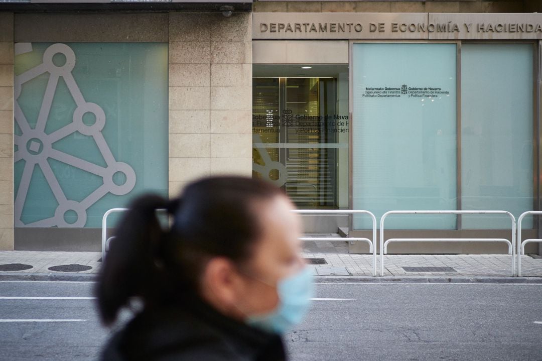 Una mujer con mascarilla pasa junto al Departamento de Economía y Hacienda un día después de que el Gobierno anunciara las medidas de desescalada por la pandemia del coronavirus