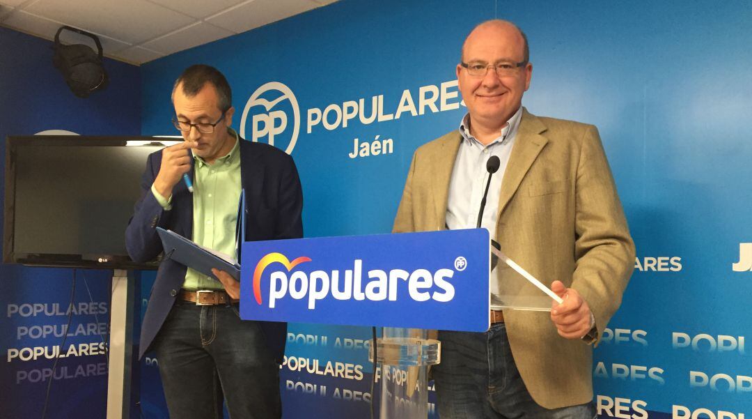 El portavoz del grupo popular en el consistorio, Javier Márquez, mira a cámara, mientras el edil del PP, Manuel Bonilla, consulta los puntos a tratar en la rueda de prensa